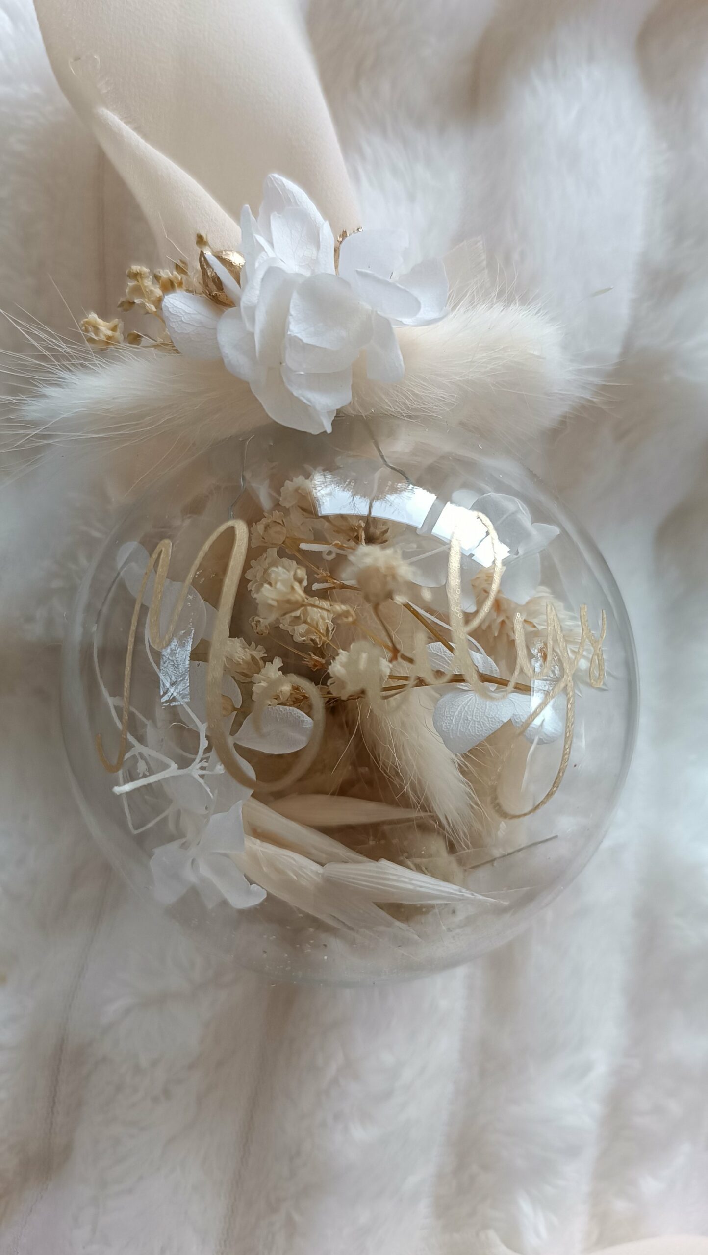 Boule de Noël en verre personnalisée avec prénom, remplie de fleurs séchées naturelles et décorée sur le dessus, idéale pour embellir le sapin et apporter une touche festive et élégante. Décoration de sapin de Noël originale, boule personnalisée en verre avec prénom gravé, contenant des fleurs séchées colorées, parfaite pour une ambiance chaleureuse et authentique. Boule de Noël artisanale en verre, personnalisable avec prénom, garnie de fleurs séchées à l’intérieur, un ornement raffiné pour sapin de Noël et décoration festive de fin d’année. Boue de noël pour mon 1er noël, joyeux noël , belles fêtes de fin d'année, cadeau à personnaliser, idée cadeau fait main à personnaliser avec prénom ou meesage. Ornement de Noël en verre transparent, boule personnalisée avec prénom et fleurs séchées, une décoration unique et naturelle pour sapin de Noël traditionnel ou moderne. Merry Christmas