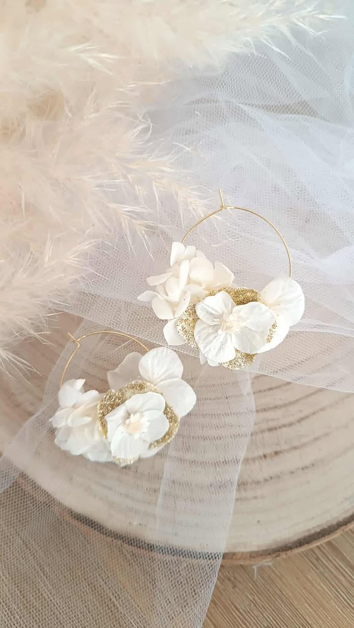 Boucles d’oreilles créoles dorées en acier inoxydable ornées de fleurs séchées blanches et dorées, création artisanale faite main. Boucles d’oreilles créoles dorées en acier inoxydable décorées de fleurs séchées blanches et dorées, bijou fait main au style naturel et élégant. bijoux femme en fleur séchées, cadeau noël femme, idée cadeau bijoux femme bohême et poétique, créoles blanches et doré en fleurs séchées. Boucle d'oreilles à offrir. Boucles d'oreilles créoles pour mariage ou èvenement. Cadeau fête des mamans, idée cadeau fait main fête des grands mères - Boucles d’oreilles créoles dorées en fleurs séchées blanches, création artisanale. Bijoux à offrir naturelle et poétique, création artisanale